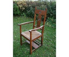 An Arts and Crafts Cotswold School armchair with lower shelf and pierced floral detail - Thumbnail 1